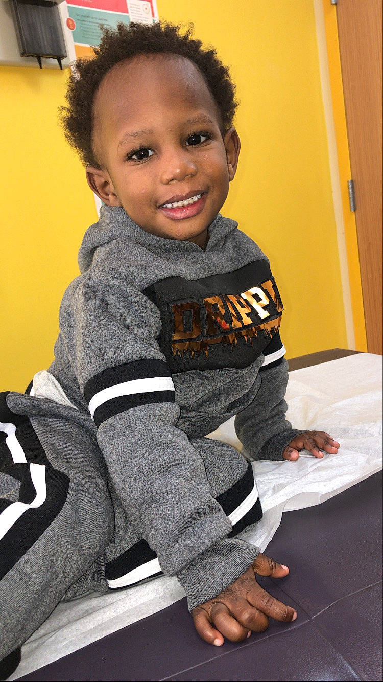 Elijah is registered to the contest to win money with this photo: baby_toddler_clothing, child, elbow, face, flooring, hair, happy, head, human_body, joy, knee, person, play, room, sitting, sleeve, smile, sportswear, t_shirt, thumb