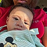 child, baby, person, face, mickey_mouse, cartoon, clothing, red_shirt, curly_hair, portrait, indoors, sunlight, expression, closeup, cuddling, adult, casual, car_seat, toddler, cute