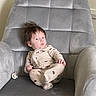 baby, child, infant, onesie, animal_print, gray_chair, armchair, pacifier, indoor, furniture, plush, seated, cute, curious, young_child, portrait, cozy, soft, home, relaxed