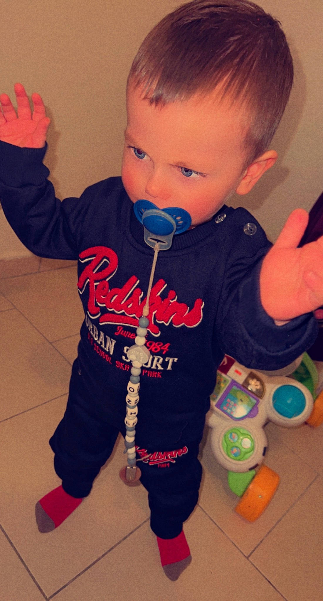 Tino a rejoint le concours — aidez-le/la à gagner de superbes lots ! baby, baby_toddler_clothing, cheek, child, cool, electric_blue, flooring, fun, gesture, happy, long_sleeved_t_shirt, neck, pattern, person, play, sleeve, sportswear, standing, t_shirt, thumb