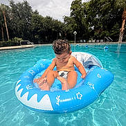 George joined the competition — help win amazing prizes! child, toddler, baby, swimming_pool, pool, inflatable_float, inner_tube, water, summer, outdoor, curly_hair, swim_diaper, sitting, barefoot, tropical, palm_trees, trees, blue_water, recreation, portrait