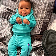 Kassio joined the competition — help win amazing prizes! baby, child, infant, smiling, blue_clothing, hoodie, pants, socks, pillow, blanket, indoor, cute, portrait, person, young_child, furniture, pattern, resting, happy, cozy