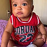 baby, child, infant, red_clothing, jersey, jordan, number_23, sneakers, white_shoes, sitting, indoors, purple_blanket, curious_expression, cute, face, arm, legs, person, portrait, young