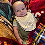 Riley joined the competition — help win amazing prizes! baby, infant, smile, bib, clothing, blanket, patterned_blanket, colorful, face, cute, young_child, portrait, happy, lying_down, soft_texture, cozy, warm, child, newborn, person