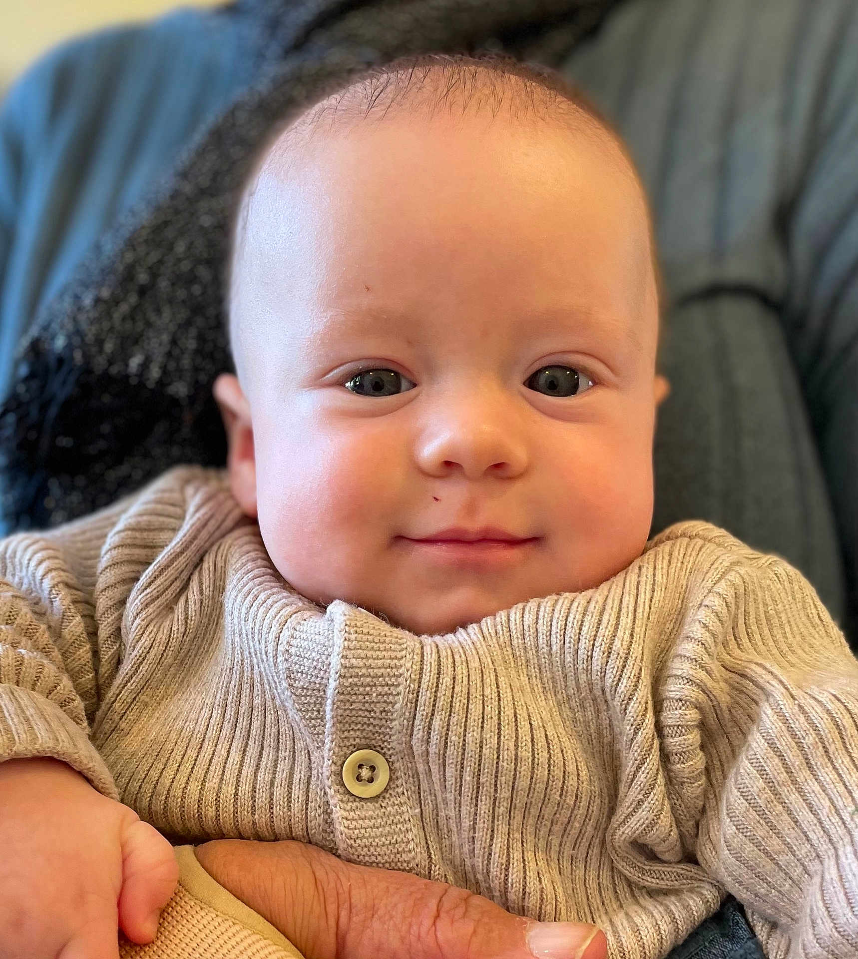 Ezra a rejoint le concours — aidez-le/la à gagner de superbes lots ! baby, infant, face, eyes, smile, hand, knitted_sweater, beige, cozy, close_up, skin, person, cute, child, portrait, warm, soft, indoor, holding, young