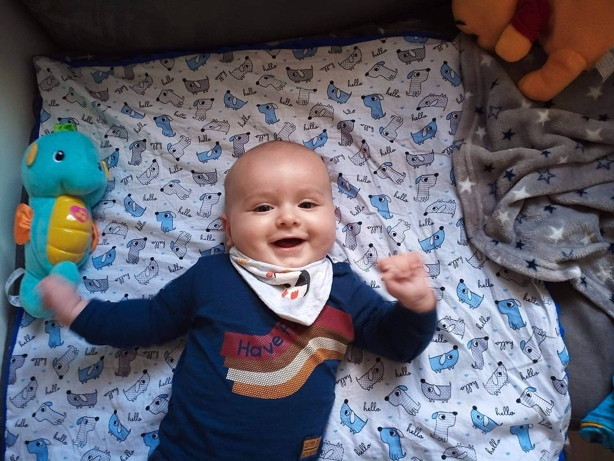 Olivier participe au concours pour gagner de l'argent avec cette photo : baby, baby_toddler_clothing, blue, child, comfort, electric_blue, finger, fun, gesture, happy, joy, linens, mouth, organ, person, purple, sitting, sleeve, smile, thumb
