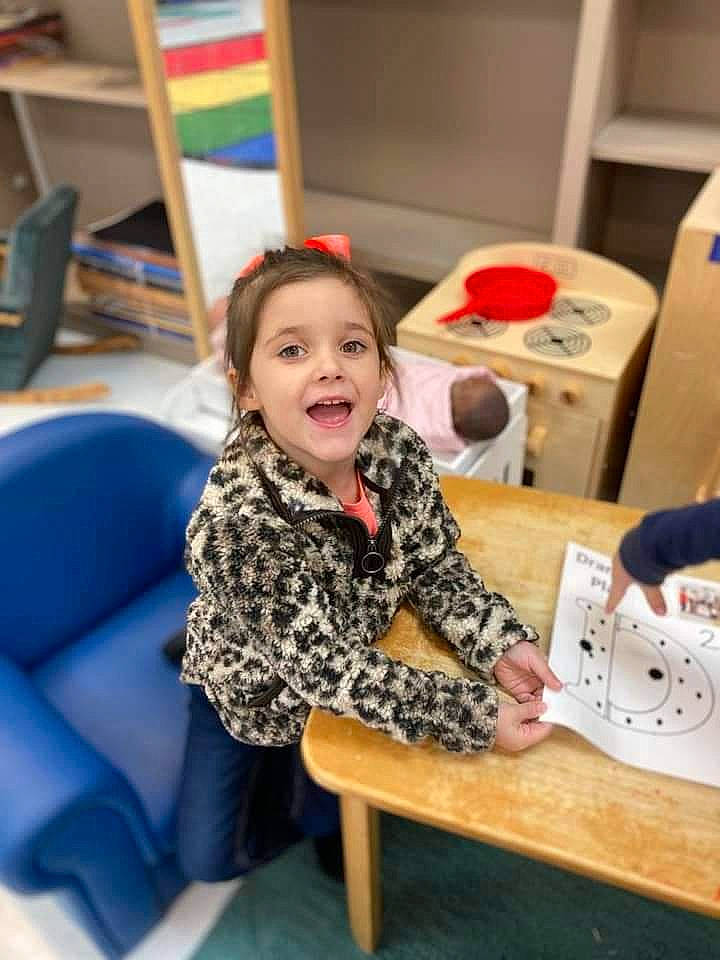 Renleigh is registered to the contest to win money with this photo: bookcase, chair, child, comfort, desk, event, flooring, fun, furniture, happy, learning, leisure, person, play, recreation, room, sitting, smile, t_shirt, table