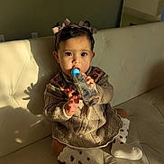 Madison joined the competition — help win amazing prizes! baby, child, girl, bottle, knitted_dress, socks, hair_bows, couch, indoor, sunlight, shadow, curious, sitting, cozy, portrait, cute, infant, warm_light, home, person