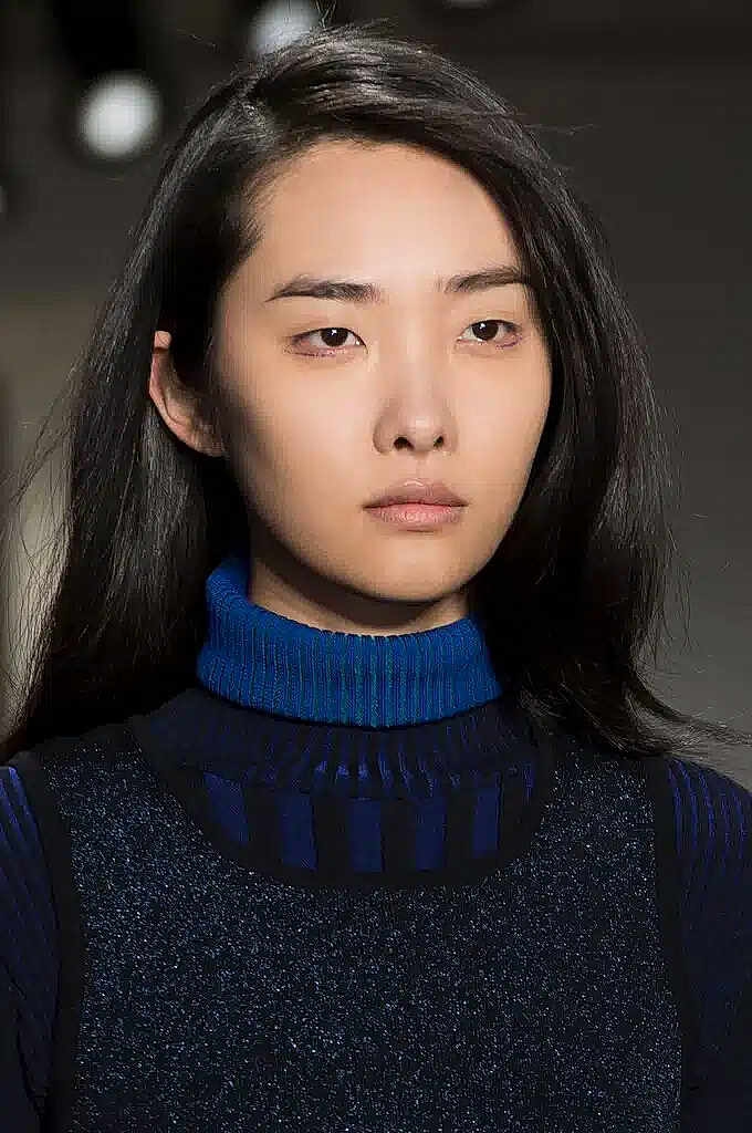 Gianna-Parissè is registered to the contest to win money with this photo: adult, black_hair, blue_turtleneck, closeup, clothing, eyebrows, face, fashion, female, hairstyle, indoor, long_hair, looking_ahead, model, person, portrait, serious, skin, studio_lighting, vest