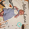 baby, infant, milestone_blanket, ocean_theme, shark, fish, turtle, months_marker, striped_romper, clothing, lying_down, cute, portrait, child, newborn, blue_and_white, patterned_blanket, soft_texture, indoors, bed