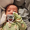 Atlas is registered to the contest to win money with this photo: baby, infant, pacifier, onesie, penguin_pattern, blanket, sleepy, cute, soft, cozy, child, newborn, clothing, bed, resting, portrait, face, comfort, indoors, person