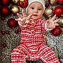 baby, child, infant, christmas, holiday, santa_hat, pajamas, red, white, ornaments, decorations, festive, reaching, hands, face, eyes, floor, patterned, celebration, cute