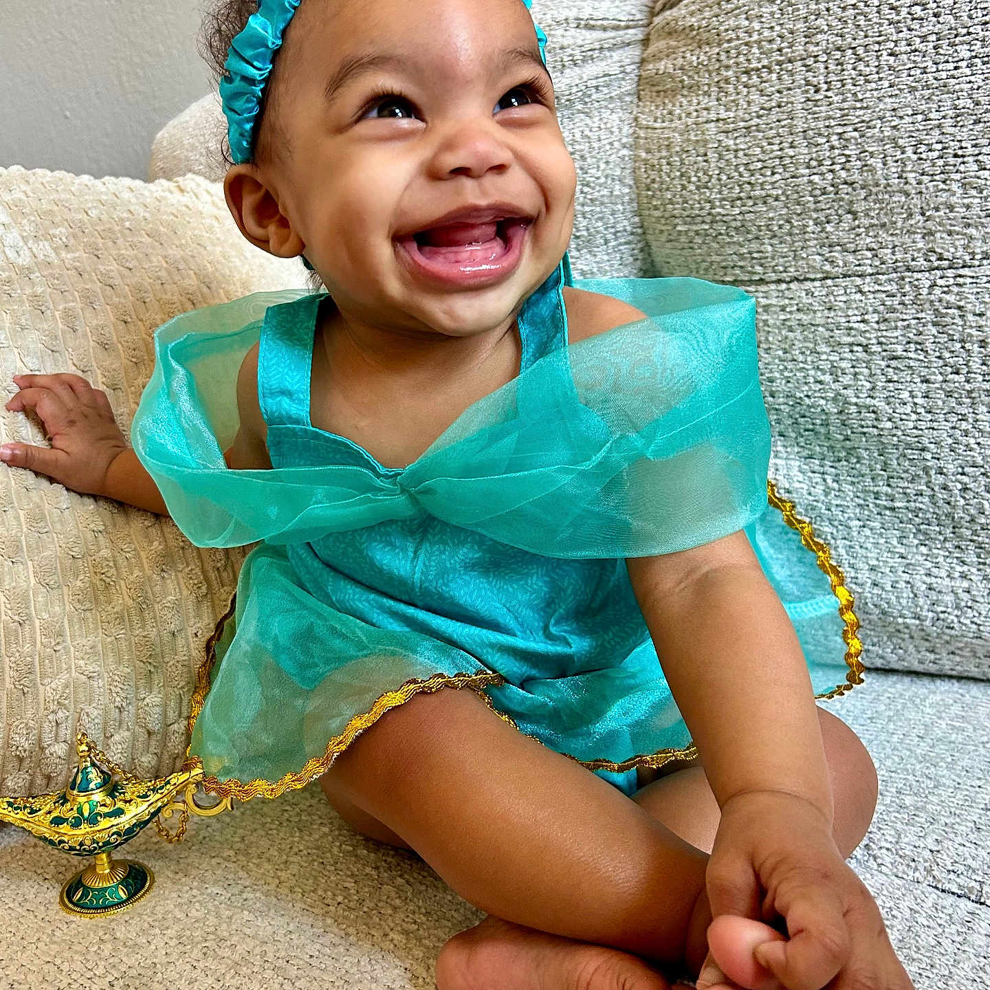 Zuri Isabella joined the competition — help win amazing prizes! barefoot, child, couch, crossed_legs, cute, dress, fabric, feet, genie_lamp, hand, happy, headband, indoor, joyful, portrait, skin, smiling, toddler, toy, young_child