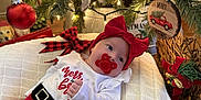 Wrenleigh joined the competition — help win amazing prizes! baby, holiday, christmas, red_bow, pacifier, pillow, christmas_tree, ornament, lights, decorations, festive, cute, indoor, smiling, child, infant, plaid_ribbon, wood_floor, cozy, dog
