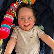 Romain a rejoint le concours — aidez-le/la à gagner de superbes lots ! baby, smiling, blue_eyes, plush_toy, caterpillar_toy, stroller, clothing, beige_shirt, teal_pants, happy, child, cute, infant, person, indoor, portrait, playful, reaching_out, seat, pacifier