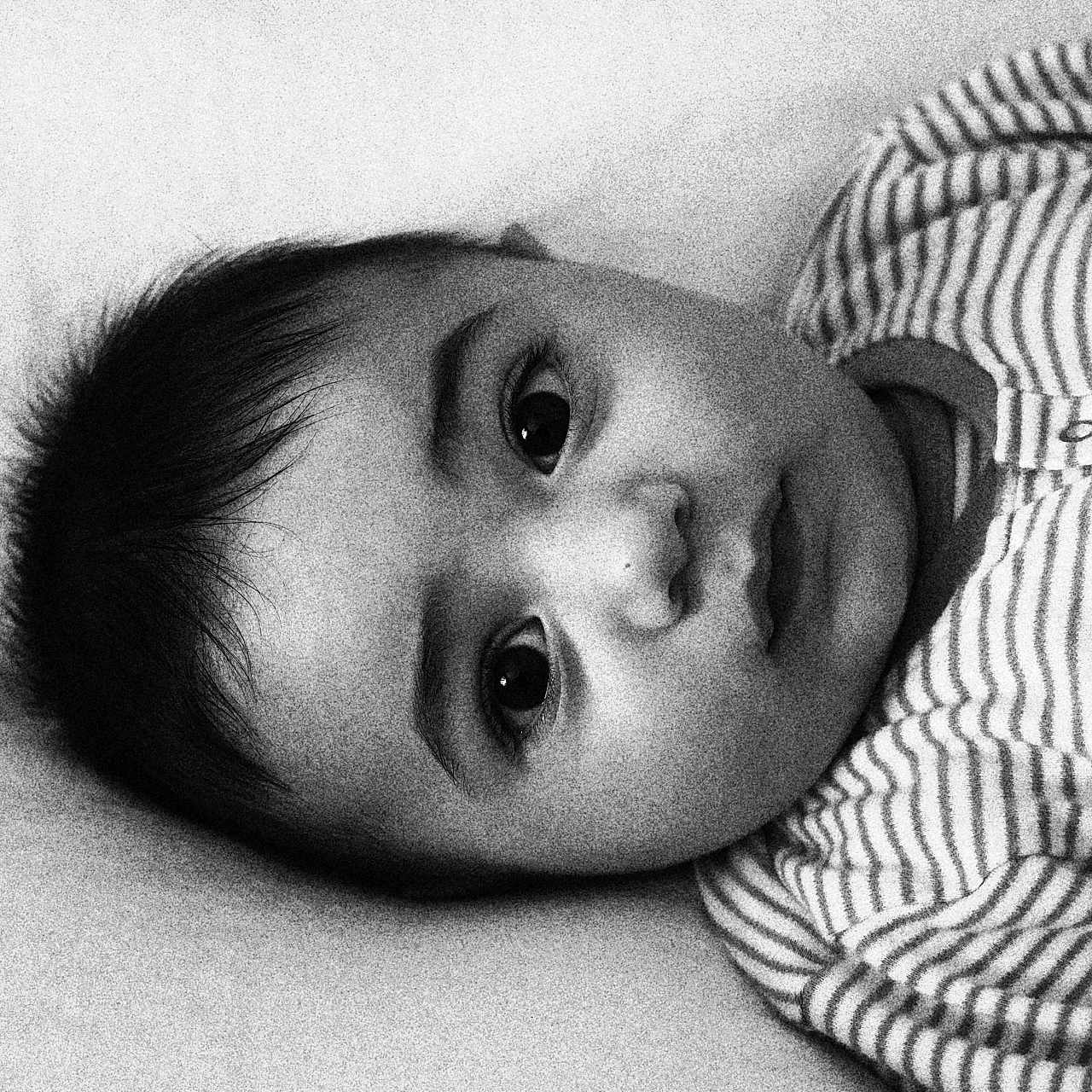 Mickaël participe au concours pour gagner de l'argent avec cette photo : baby, black_and_white, child, close_up, curious_eyes, cute, expressionless, face, head, indoors, infant, lying_down, monochrome, newborn, person, portrait, sleepwear, soft_lighting, striped_clothing, young_child
