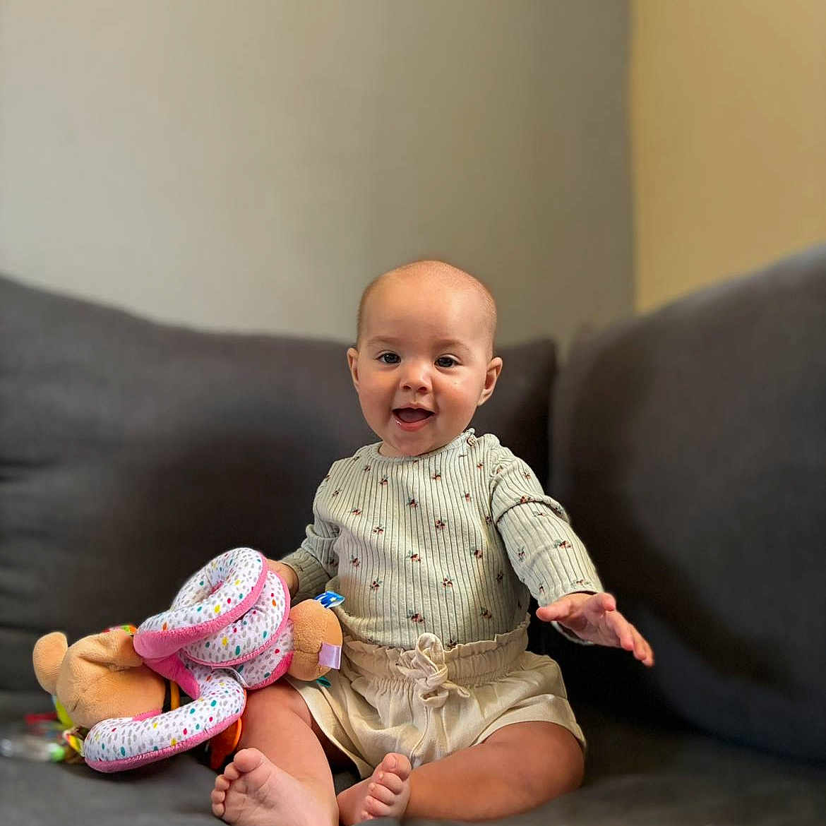 Alénya a rejoint le concours — aidez-le/la à gagner de superbes lots ! baby, barefoot, child, clothing, couch, cozy, cute, expression, face, furniture, happy, home, indoor, infant, person, plush_toy, reaching, sitting, smiling, toy