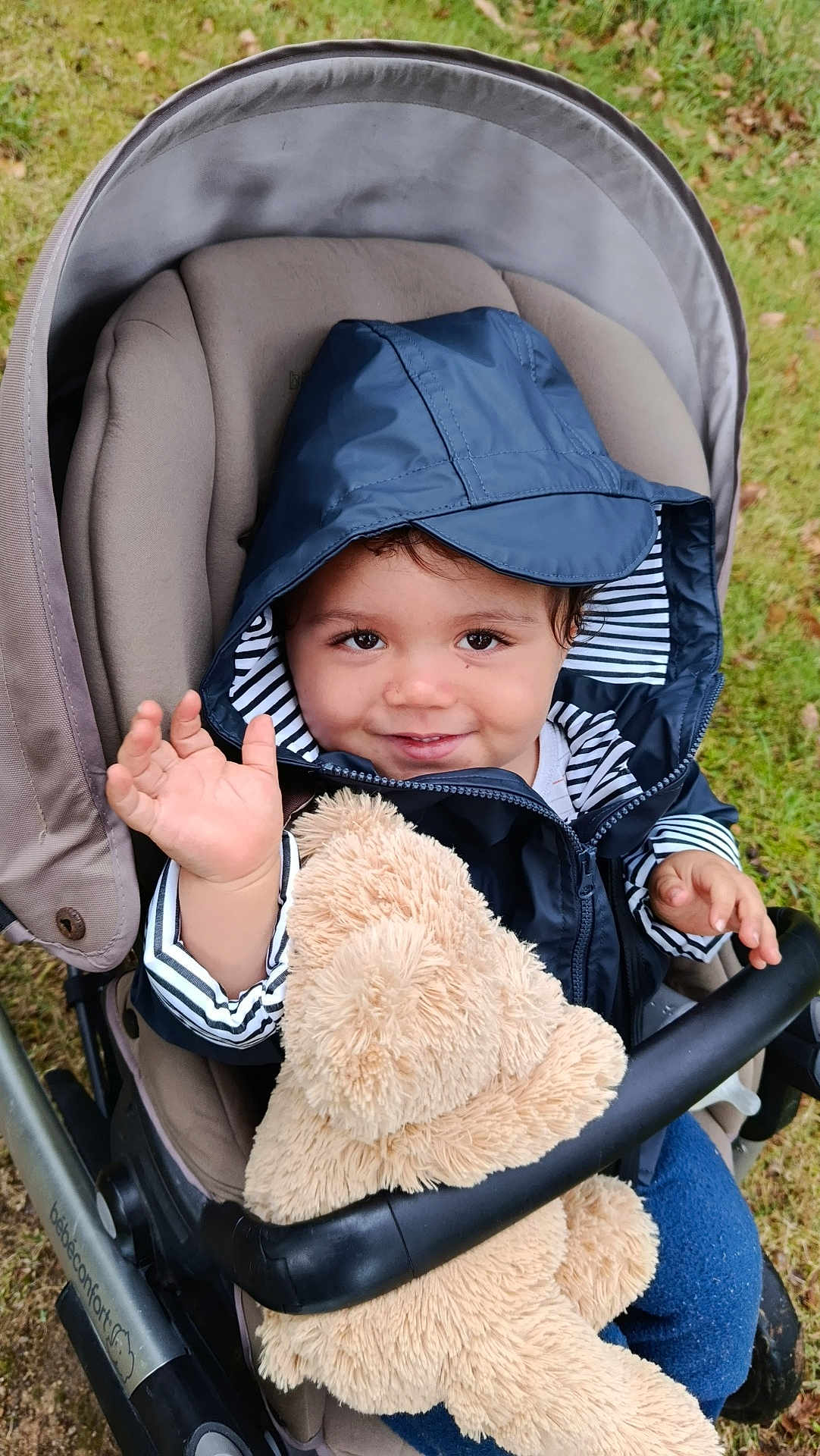 Noa a rejoint le concours — aidez-le/la à gagner de superbes lots ! toddler, child, stroller, teddy_bear, hooded_jacket, smiling, waving, outdoor, grass, toy, baby, person, cute, happy, seat, clothing, hand, face, portrait, baby_carriage