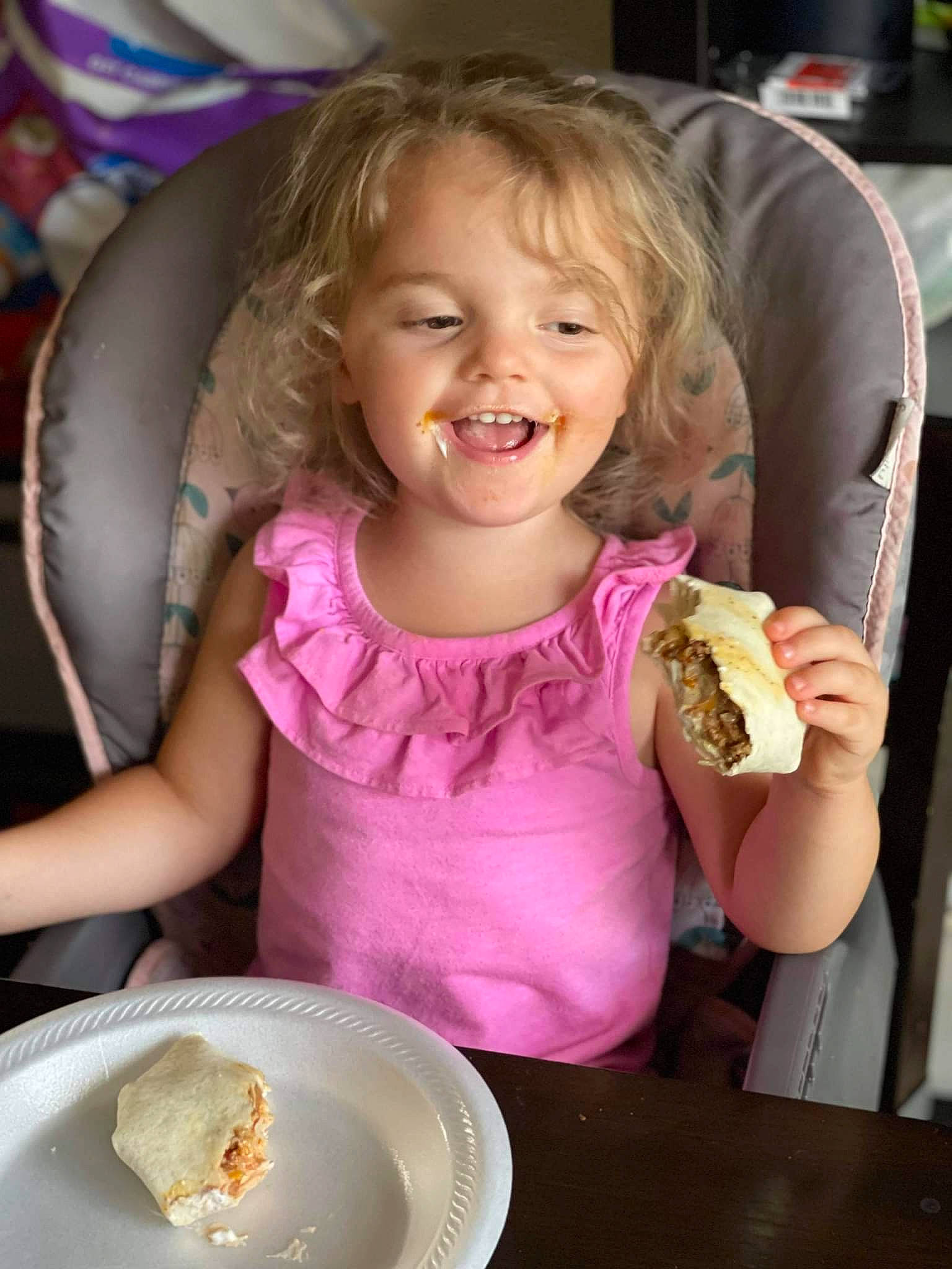 Autumn is registered to the contest to win money with this photo: chair, child, comfort_food, cuisine, dessert, dish, dishware, face, food, happy, ingredient, joy, person, pink, plate, smile, spoon, summer, sweetness, table