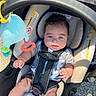 Karri is registered to the contest to win money with this photo: baby, infant, child, car_seat, harness, portrait, smiling, face, eyes, hair, outdoor, sunlight, toy, plush_toy, stroller, sitting, clothing, gray_shirt, pavement, photography
