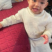 Mikia Marie Owens is registered to the contest to win money with this photo: toddler, child, smiling, white_clothing, sneakers, indoor, couch, quilted, pillow, curious, standing, person, face, cute, fashion, home, furniture, happy, young_child, footwear