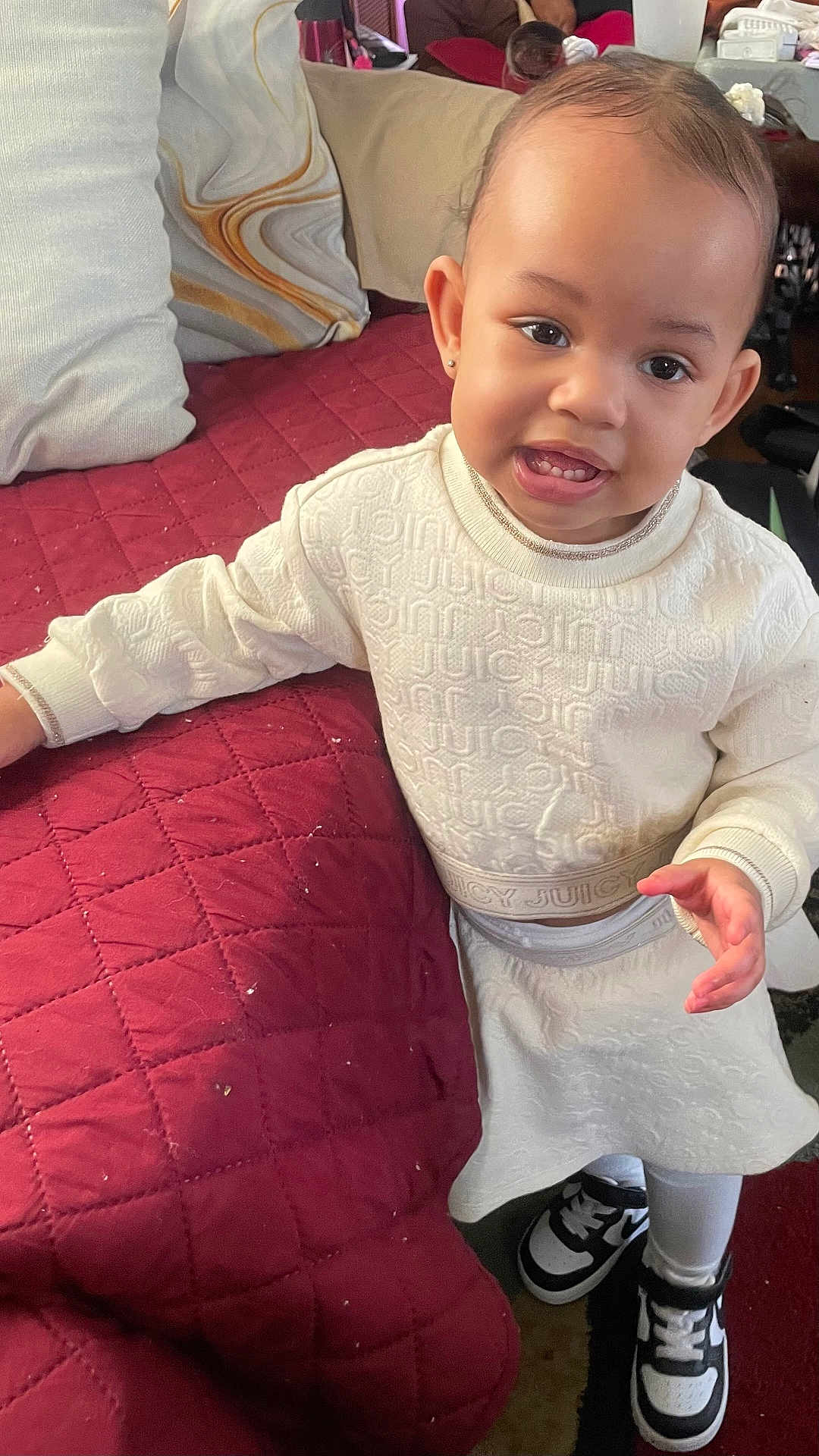 Mikia Marie Owens is registered to the contest to win money with this photo: toddler, child, smiling, white_clothing, sneakers, indoor, couch, quilted, pillow, curious, standing, person, face, cute, fashion, home, furniture, happy, young_child, footwear