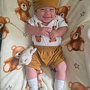 Emiliano is registered to the contest to win money with this photo: baby, newborn, infant, smiling, portrait, lying_down, teddy_bears, blanket, plush_toy, bunny, hat, clothing, brown_outfit, socks, nursery, cozy, indoors, happy, cute, photography