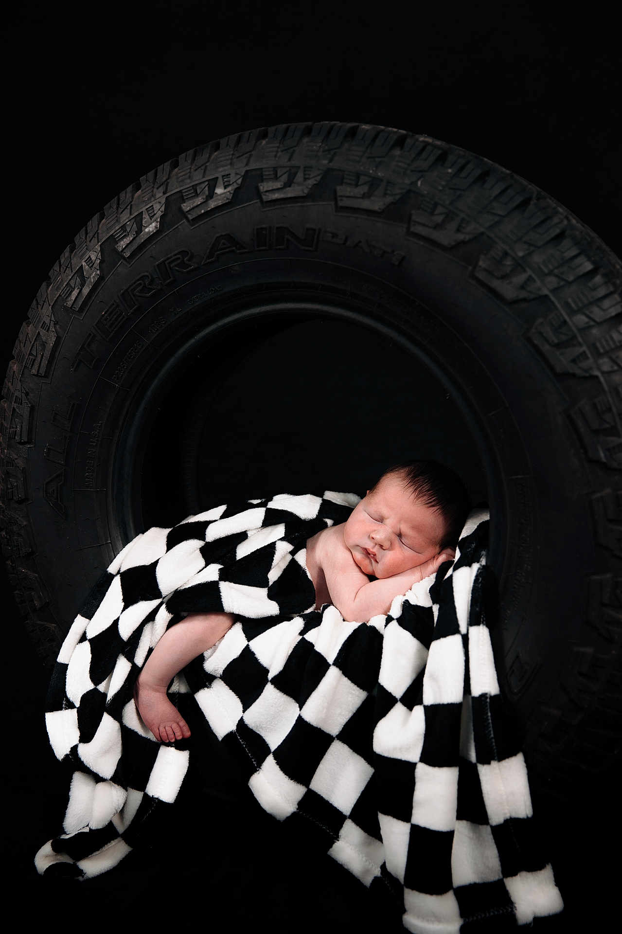 Axel joined the competition — help win amazing prizes! baby, sleeping, blanket, black_and_white, checkered, tire, toddler, infant, soft_texture, cozy, dark_background, portrait, cute, peaceful, resting, newborn, studio_photo, child, wrapped, foot