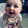 baby, smiling, child, face, blue_eyes, plush_toy, lion_toy, sitting, indoors, floral_pattern, happy, cute, infant, clothing, long_sleeve, floor, home, portrait, close_up, young_child