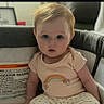 Emily is registered to the contest to win money with this photo: baby, infant, child, playpen, rainbow, pants, shirt, sitting, indoors, curious, cute, skin, foot, hand, face, eyes, hair, phone_screen, notification, clothing