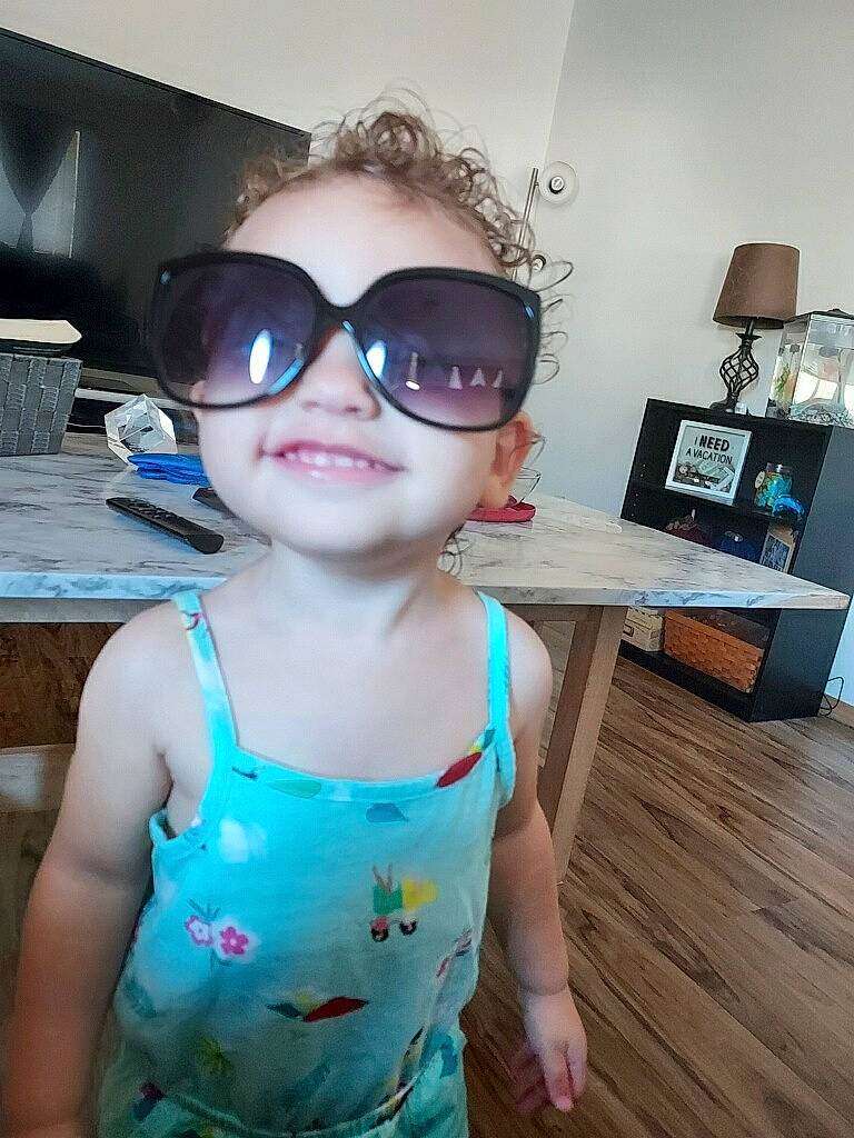 Hana is registered to the contest to win money with this photo: baby_toddler_clothing, blue, cool, eye, eyewear, facial_expression, glasses, goggles, hair, happy, head, person, personal_protective_equipment, pink, skin, smile, standing, sunglasses, toddler, vision_care