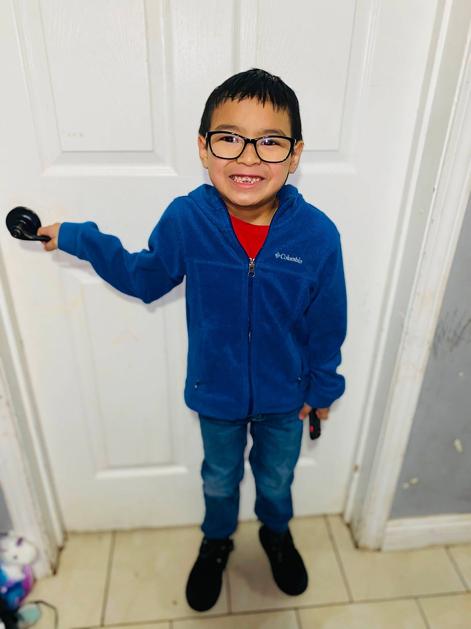 Elijah is registered to the contest to win money with this photo: arm, baby_toddler_clothing, clothing, collar, denim, dress_shirt, electric_blue, eyewear, flooring, glasses, happy, human_body, joint, joy, outerwear, person, shoulder, sleeve, standing, t_shirt
