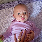 Journey is registered to the contest to win money with this photo: baby, infant, hand, purple_clothing, blanket, face, blue_eyes, person, skin, nail_polish, ring, holding_hand, lying_down, portrait, close_up, soft_texture, indoor, cute, expression, child