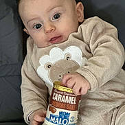Malo participe au concours pour gagner de l'argent avec cette photo : baby, beige_outfit, caramel_dessert, child, cozy_clothing, curious, cute, dessert_cup, eyes, face, food_container, hand, holding, indoor, infant, lion_applique, mouth, portrait, sitting, soft_texture