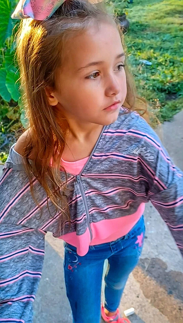 Adelyn is registered to the contest to win money with this photo: beauty, brown_hair, child, clothing, cool, denim, facial_expression, grass, hair, hairstyle, happy, iris, lip, long_hair, people_in_nature, person, plant, skin, sleeve, summer