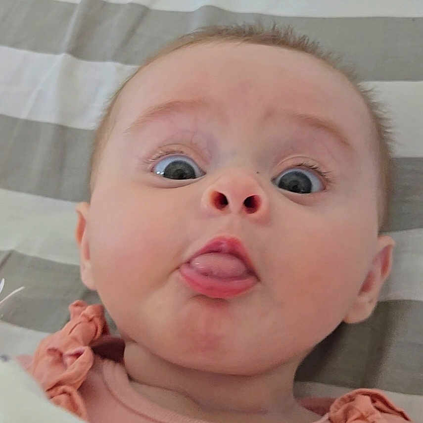 Sierrah participe au concours pour gagner de l'argent avec cette photo : baby, blanket, child, clothing, cute, expression, face, funny, head, infant, lying_down, mouth, peach, person, portrait, ruffles, skin, striped, tongue, wide_eyes