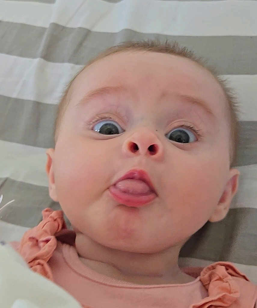 Sierrah participe au concours pour gagner de l'argent avec cette photo : baby, blanket, child, clothing, cute, expression, face, funny, head, infant, lying_down, mouth, peach, person, portrait, ruffles, skin, striped, tongue, wide_eyes