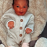 Miyah participe au concours pour gagner de l'argent avec cette photo : baby, infant, onesie, knitwear, blanket, hat, slippers, smile, cute, cozy, soft_texture, child, newborn, warm_clothing, indoor, lying_down, face, hand, footwear, sleeping_bag