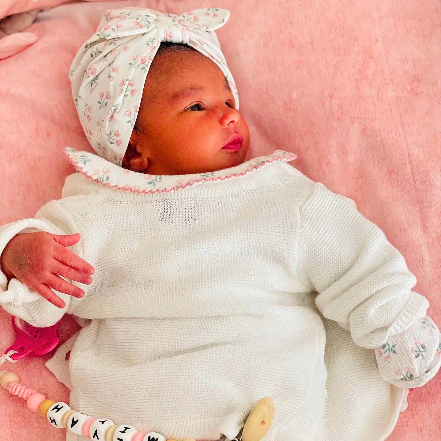 Miyah participe au concours pour gagner de l'argent avec cette photo : baby, baby_girl, blanket, child, closeup, cute, floral_pattern, hand, headband, indoors, infant, lying_down, newborn, pacifier_clip, peaceful, pink_background, portrait, sleepy, soft_texture, white_clothing