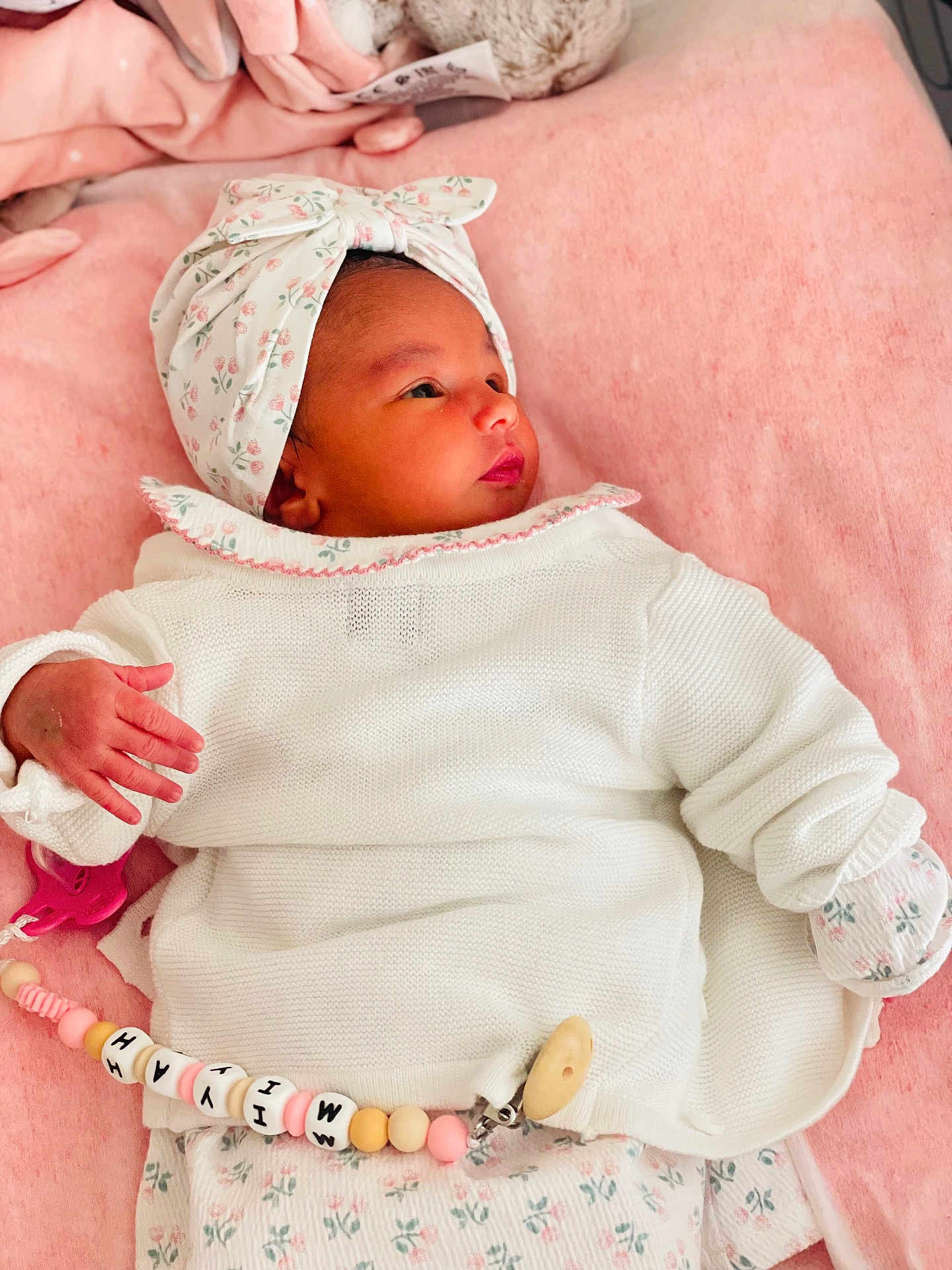 Miyah participe au concours pour gagner de l'argent avec cette photo : baby, newborn, infant, blanket, headband, white_clothing, floral_pattern, pacifier_clip, lying_down, pink_background, soft_texture, cute, peaceful, sleepy, indoors, child, portrait, baby_girl, hand, closeup
