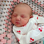 Anastasia is registered to the contest to win money with this photo: baby, newborn, infant, sleeping, blanket, crochet, onesie, cherry_pattern, closed_eyes, face, head, cheeks, swaddle, cozy, soft_texture, pink, gray, portrait, resting, nursery