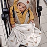 baby, beanie, blanket, bottle, child, comforter, cozy, cute, hand, indoors, jacket, mustard_color, portrait, seat, shelf, shopping, stroller, supermarket, tiled_floor, wide_eyes