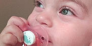 Tamila participe au concours pour gagner de l'argent avec cette photo : baby, child, close_up, curious, cute, expression, face, green_eyes, hand, holding, indoor, infant, looking_up, onesie, pacifier, pink, short_hair, skin, toddler, whale