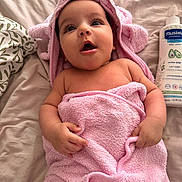 Eline participe au concours pour gagner de l'argent avec cette photo : baby, infant, pink_towel, hooded_towel, bed, lotion_bottle, curious_expression, blanket, soft_texture, wrapped, child, cute, skin, hands, awake, indoors, resting, newborn, portrait, towel