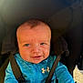 baby, blue_jacket, child, clothing, cute, eyes, face, happy, head_support, infant, outdoor, person, portrait, seat, smiling, straps, stroller, sunlight, under_armour_logo, young_child