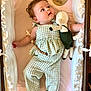 baby, bed, child, clothing, crib, cute, fabric, five_months, gazing, green_outfit, indoors, infant, milestone, person, plush_toy, portrait, resting, smiling, soft_toy, wooden_plaque