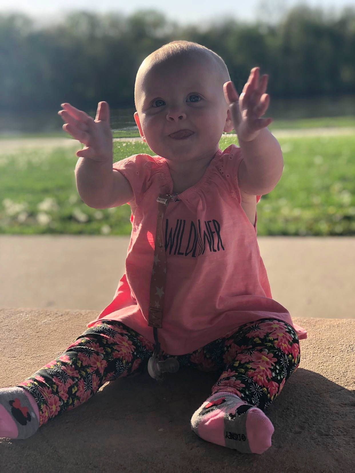 Maddyson is registered to the contest to win money with this photo: baby, baby_toddler_clothing, child, face, finger, flash_photography, fun, gesture, grass, happy, leisure, people_in_nature, person, pink, plant, sitting, sky, sleeve, smile, standing
