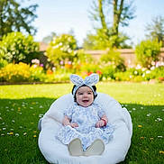 Azalea joined the competition — help win amazing prizes! baby, child, smiling, dress, headband, bunny_ears, cushion, grass, flowers, garden, outdoor, sunny, greenery, happy, person, infant, nature, playful, cute, portrait