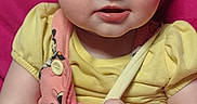 Nalah is registered to the contest to win money with this photo: baby, child, infant, face, eyes, hands, clothing, yellow_shirt, pink_overalls, cartoon_print, sitting, pink_background, cute, portrait, skin, expression, young, person, indoor, closeup