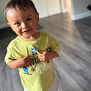Amilio is registered to the contest to win money with this photo: background, child, cute, donald_duck, face, floor, hair, hands, happy, home, indoor, light, mickey_mouse, person, portrait, shorts, smiling, standing, toddler, yellow_shirt